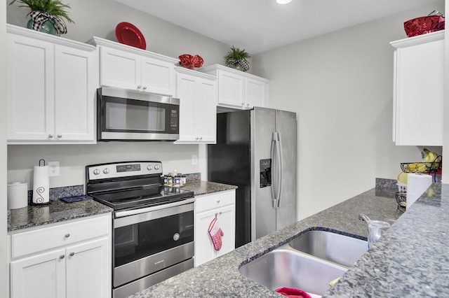 kitchen featuring dark stone counters, sink, stainless steel appliances, and white cabinetry