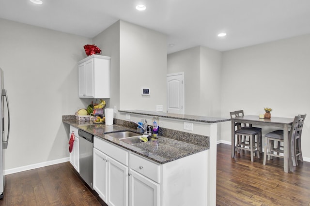 kitchen featuring white cabinetry, appliances with stainless steel finishes, kitchen peninsula, and dark stone counters