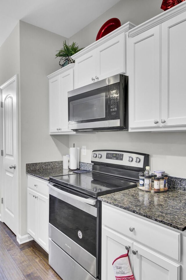 kitchen with white cabinets, appliances with stainless steel finishes, and dark hardwood / wood-style floors