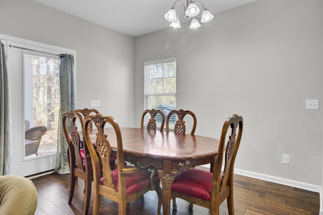 dining room with dark wood-type flooring and an inviting chandelier