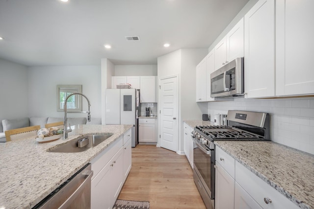 452 Minim St, Charleston, SC 29414 - kitchen featuring appliances with stainless steel finishes, a sink, light wood-style floors, white cabinets, and recessed lighting