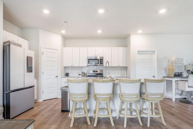 452 Minim St, Charleston, SC 29414 - kitchen with stainless steel appliances, white cabinetry, a kitchen breakfast bar, light wood-style flooring, and recessed lighting
