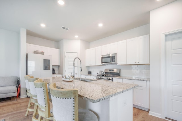 452 Minim St, Charleston, SC 29414 - kitchen featuring stainless steel appliances, a sink, an island with sink, a breakfast bar, and white cabinets