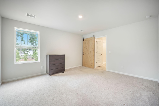 452 Minim St, Charleston, SC 29414 - unfurnished bedroom with baseboards, carpet floors, and a barn door