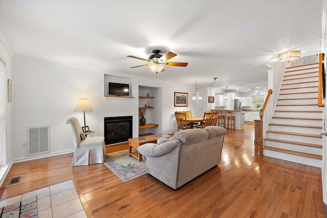 living room with crown molding, ceiling fan, and light hardwood / wood-style flooring