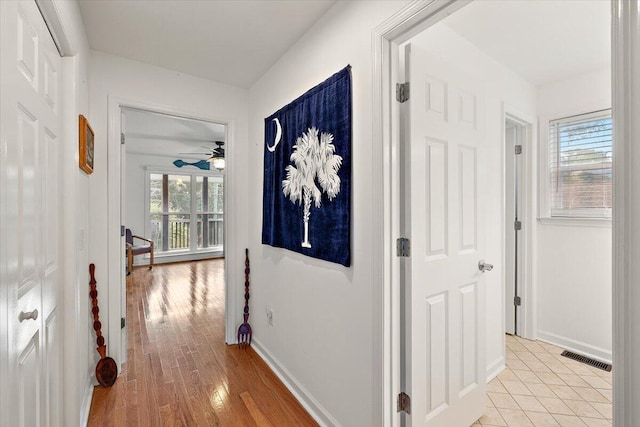 hall with a healthy amount of sunlight and light hardwood / wood-style flooring