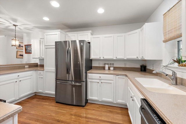 kitchen featuring stainless steel appliances, light hardwood / wood-style floors, sink, white cabinets, and pendant lighting