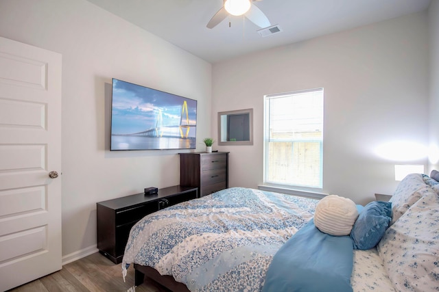 bedroom with a ceiling fan, visible vents, wood finished floors, and baseboards