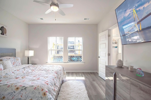 bedroom featuring baseboards, ceiling fan, light wood-style floors, and visible vents