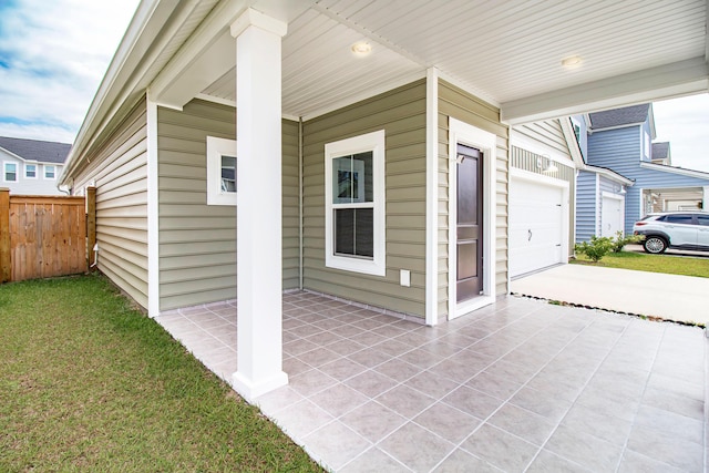 view of patio featuring concrete driveway, fence, and a garage