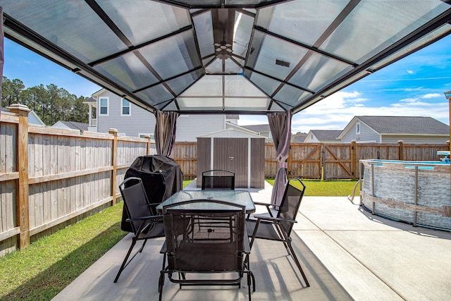 view of patio with outdoor dining area, a fenced in pool, an outdoor structure, a shed, and a fenced backyard