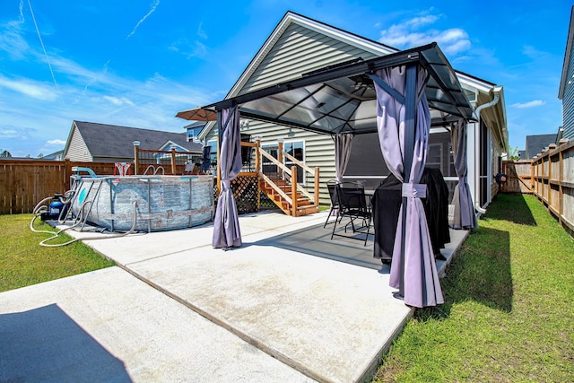 rear view of house with a fenced backyard, a gazebo, a fenced in pool, and a yard