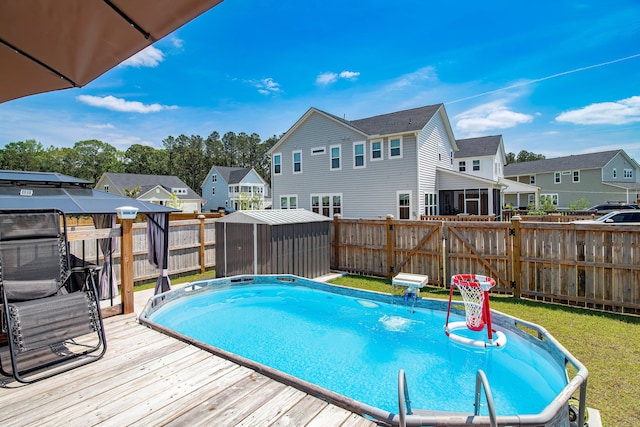 view of pool featuring an outdoor structure, a shed, a residential view, a wooden deck, and a fenced backyard