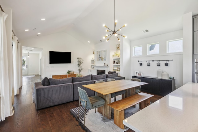dining room with a chandelier, dark wood finished floors, lofted ceiling, recessed lighting, and a fireplace
