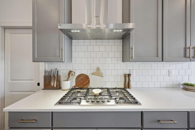 kitchen featuring gray cabinetry, extractor fan, stainless steel gas cooktop, decorative backsplash, and light stone counters