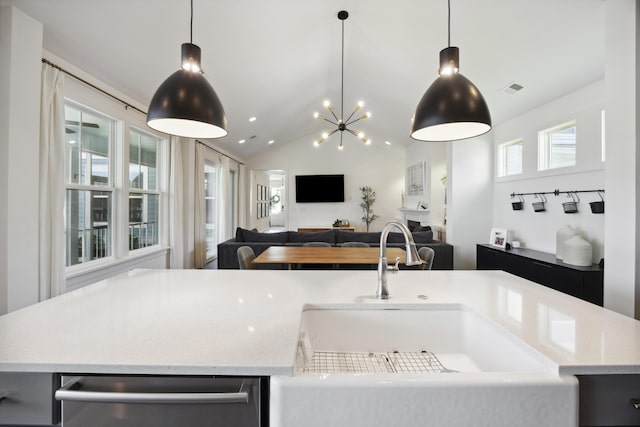 kitchen with a sink, a center island with sink, open floor plan, hanging light fixtures, and light stone countertops