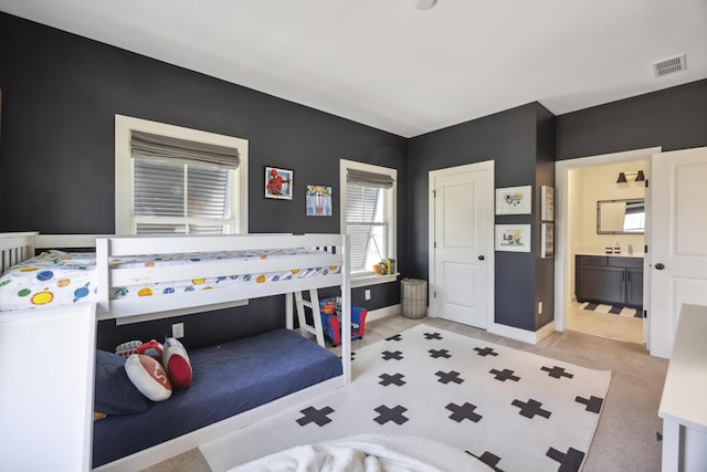 bedroom with light carpet, baseboards, and ensuite bath