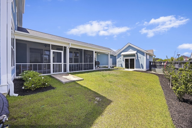 view of yard featuring a ceiling fan, a sunroom, and an outbuilding