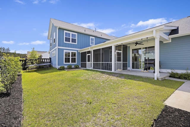 rear view of house featuring ceiling fan, a lawn, a sunroom, and a patio
