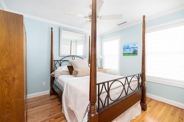 bedroom featuring a ceiling fan, crown molding, light wood-type flooring, visible vents, and baseboards