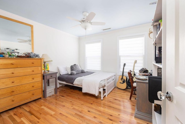 bedroom featuring light wood finished floors, crown molding, a ceiling fan, and visible vents
