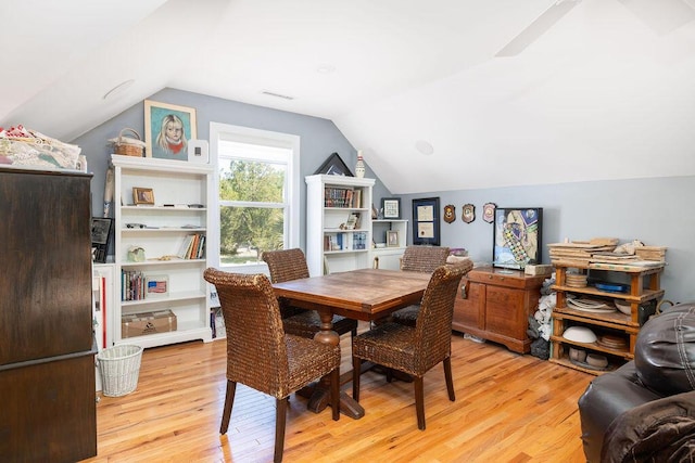 dining room with light wood-style flooring, visible vents, and vaulted ceiling