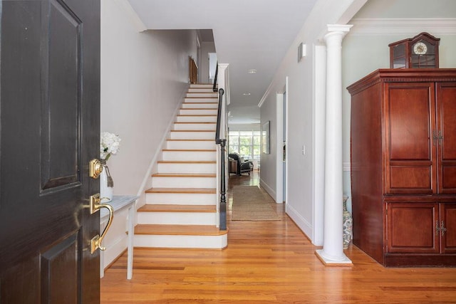 entrance foyer featuring crown molding, light wood-style floors, stairway, and ornate columns