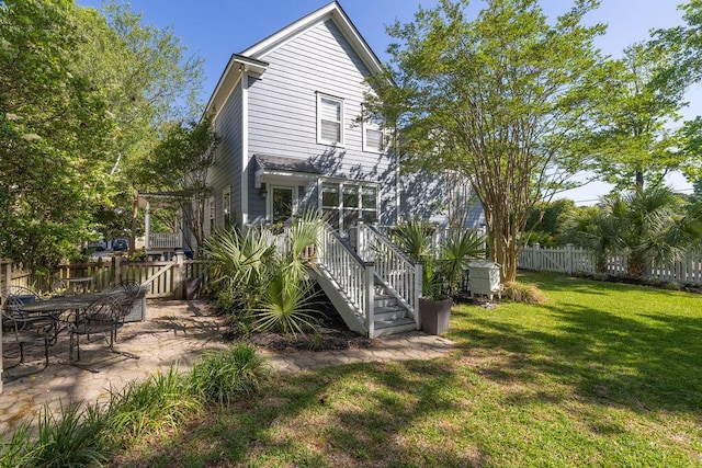 rear view of house featuring a yard, a patio area, stairway, and fence