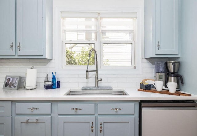 kitchen featuring a sink, stainless steel dishwasher, light countertops, decorative backsplash, and gray cabinetry