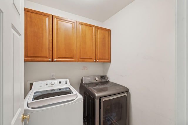 clothes washing area with cabinets and washer and dryer