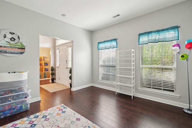 bedroom with multiple windows and dark wood-type flooring