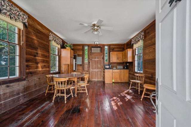 dining room with a wealth of natural light, wooden walls, and dark hardwood / wood-style floors