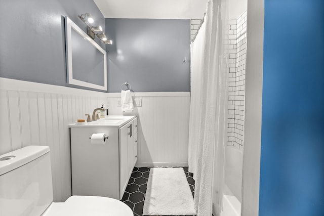 full bath featuring a shower with shower curtain, vanity, toilet, and wainscoting