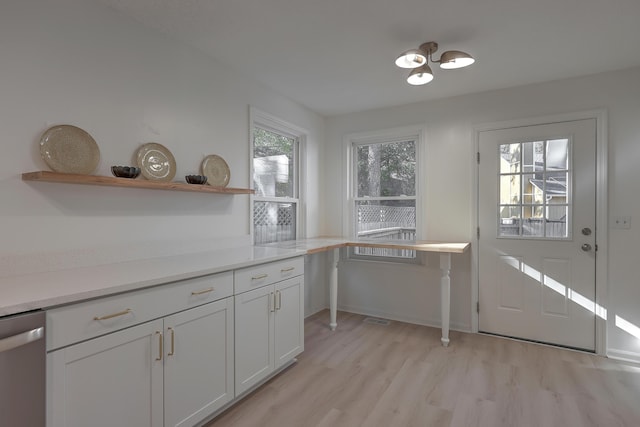 kitchen with white cabinets, light hardwood / wood-style floors, and stainless steel dishwasher