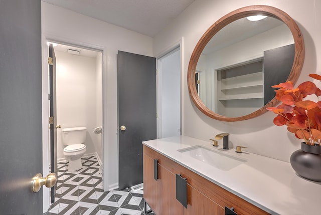 bathroom featuring a textured ceiling, vanity, and toilet