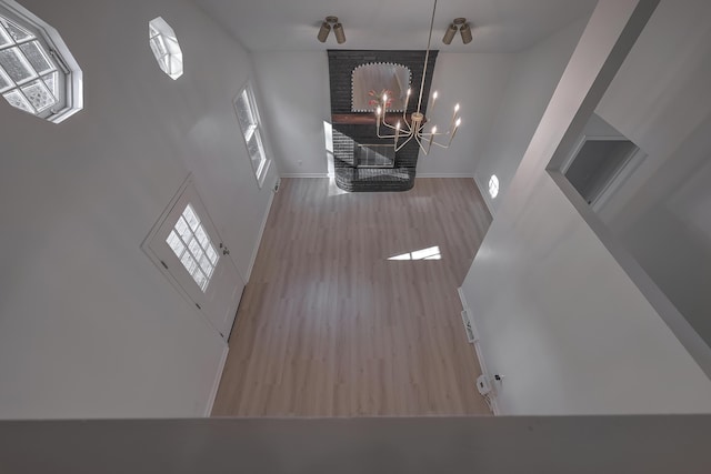 unfurnished living room featuring ceiling fan with notable chandelier, a high ceiling, and light wood-type flooring