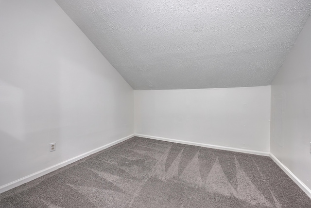 bonus room with carpet, lofted ceiling, and a textured ceiling