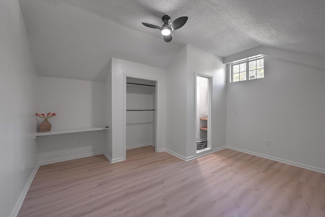 unfurnished bedroom with a textured ceiling, ceiling fan, vaulted ceiling, and light wood-type flooring