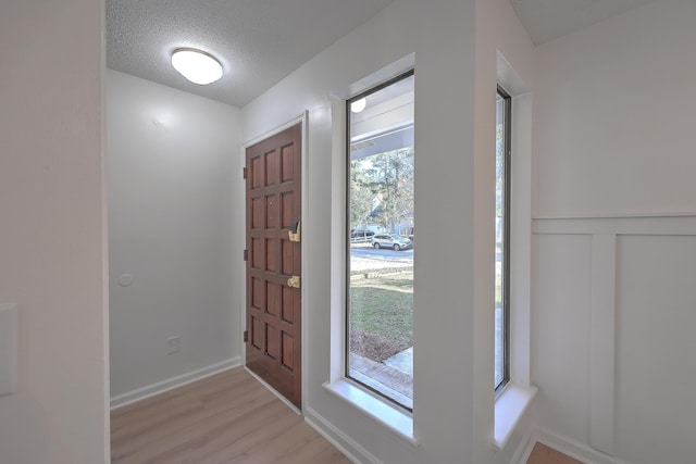 entryway with light hardwood / wood-style floors and a textured ceiling