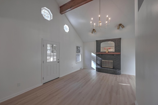 unfurnished living room featuring high vaulted ceiling, a brick fireplace, light hardwood / wood-style flooring, beam ceiling, and a chandelier