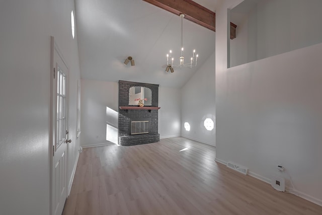 unfurnished living room featuring high vaulted ceiling, an inviting chandelier, a brick fireplace, light hardwood / wood-style flooring, and beam ceiling