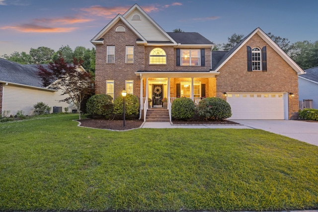 traditional-style house with brick siding, driveway, an attached garage, and a yard