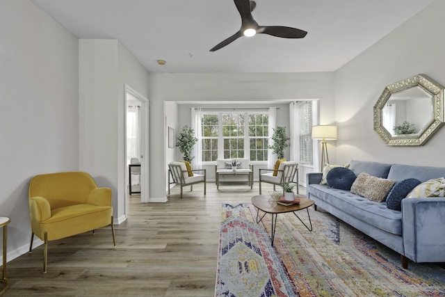 living room featuring ceiling fan, baseboards, and wood finished floors