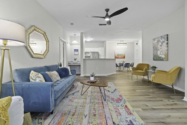 living area featuring a ceiling fan, baseboards, visible vents, and wood finished floors