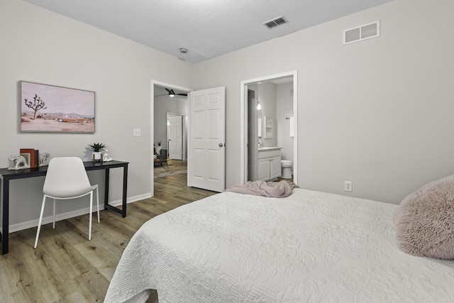 bedroom featuring ensuite bath, wood finished floors, visible vents, and baseboards