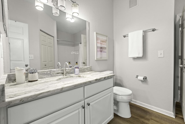 full bath with baseboards, visible vents, toilet, wood finished floors, and vanity