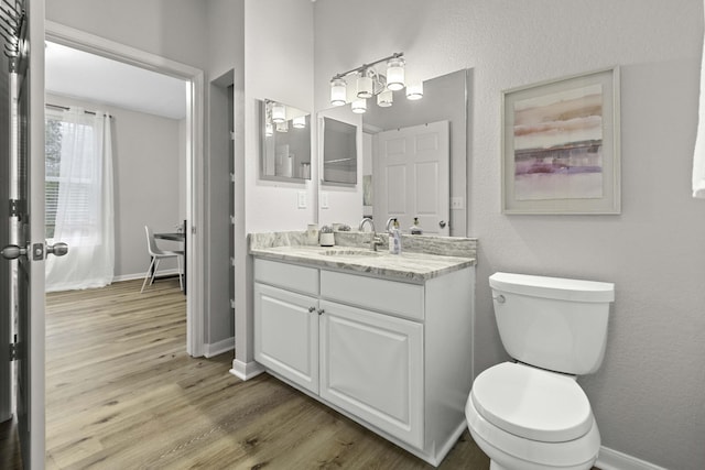 bathroom featuring toilet, baseboards, wood finished floors, and vanity