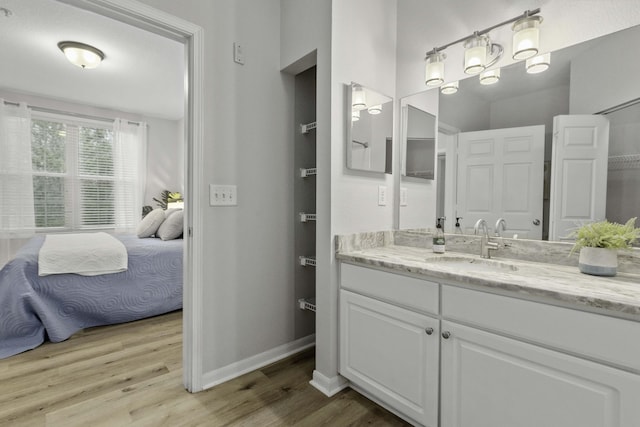 ensuite bathroom featuring baseboards, vanity, ensuite bath, and wood finished floors