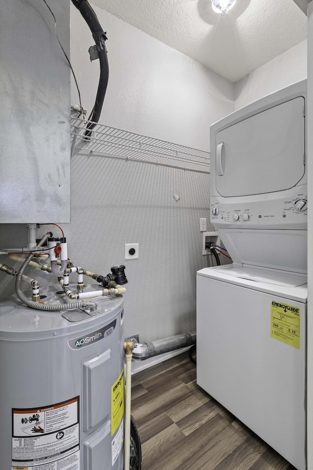 clothes washing area with laundry area, stacked washer / dryer, wood finished floors, electric water heater, and a textured ceiling