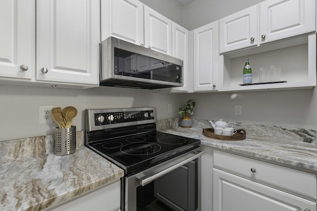 kitchen with open shelves, appliances with stainless steel finishes, white cabinetry, and light stone countertops